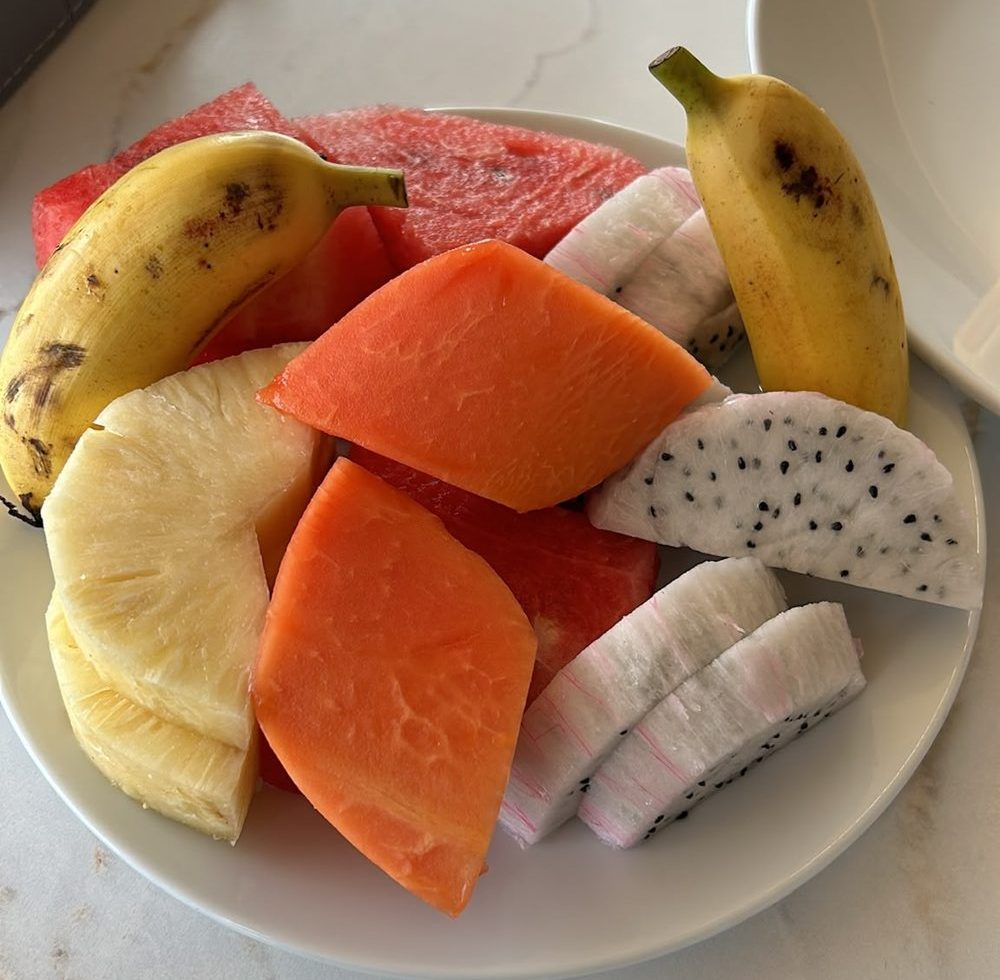 Plato de papaya, piña, sandía, fruta del dragón y plátanos pequeños