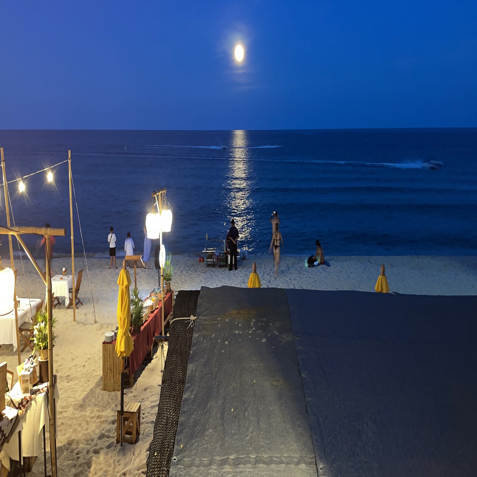 Beachfront restaurant at night with the moon over the sea