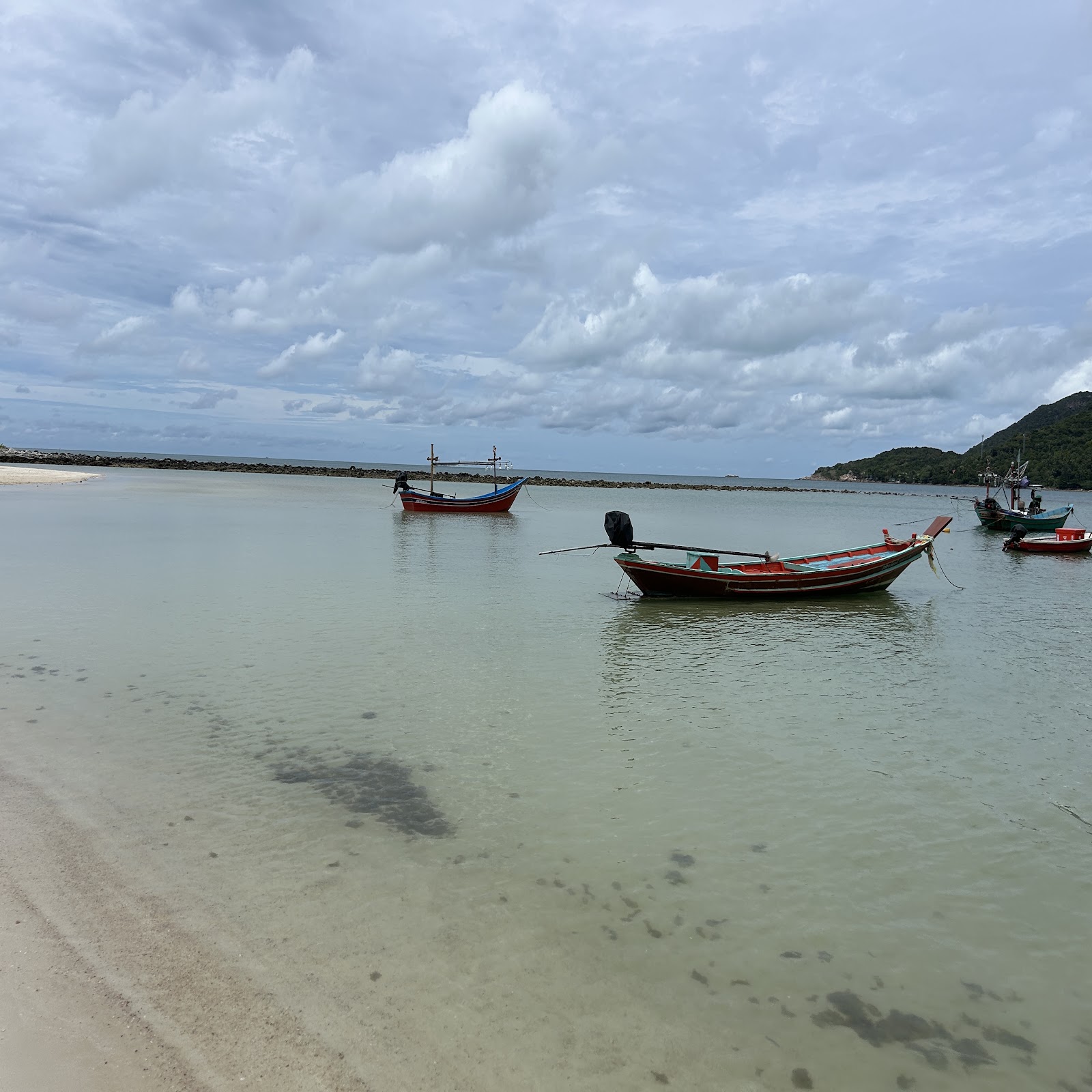Longtail boats anchored on a calm shallow bay in Koh Samui
